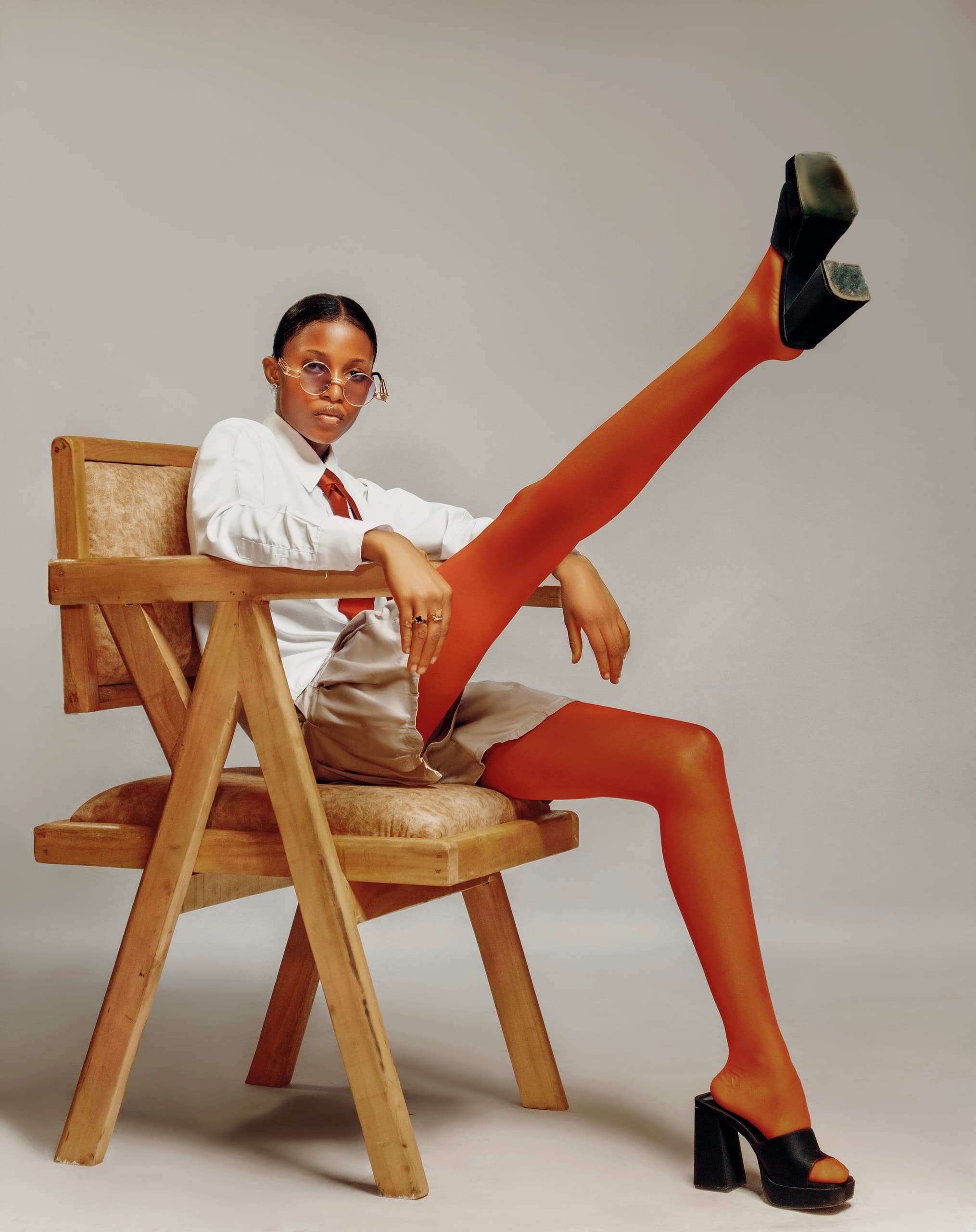 Fashion model posing across a wooden chair